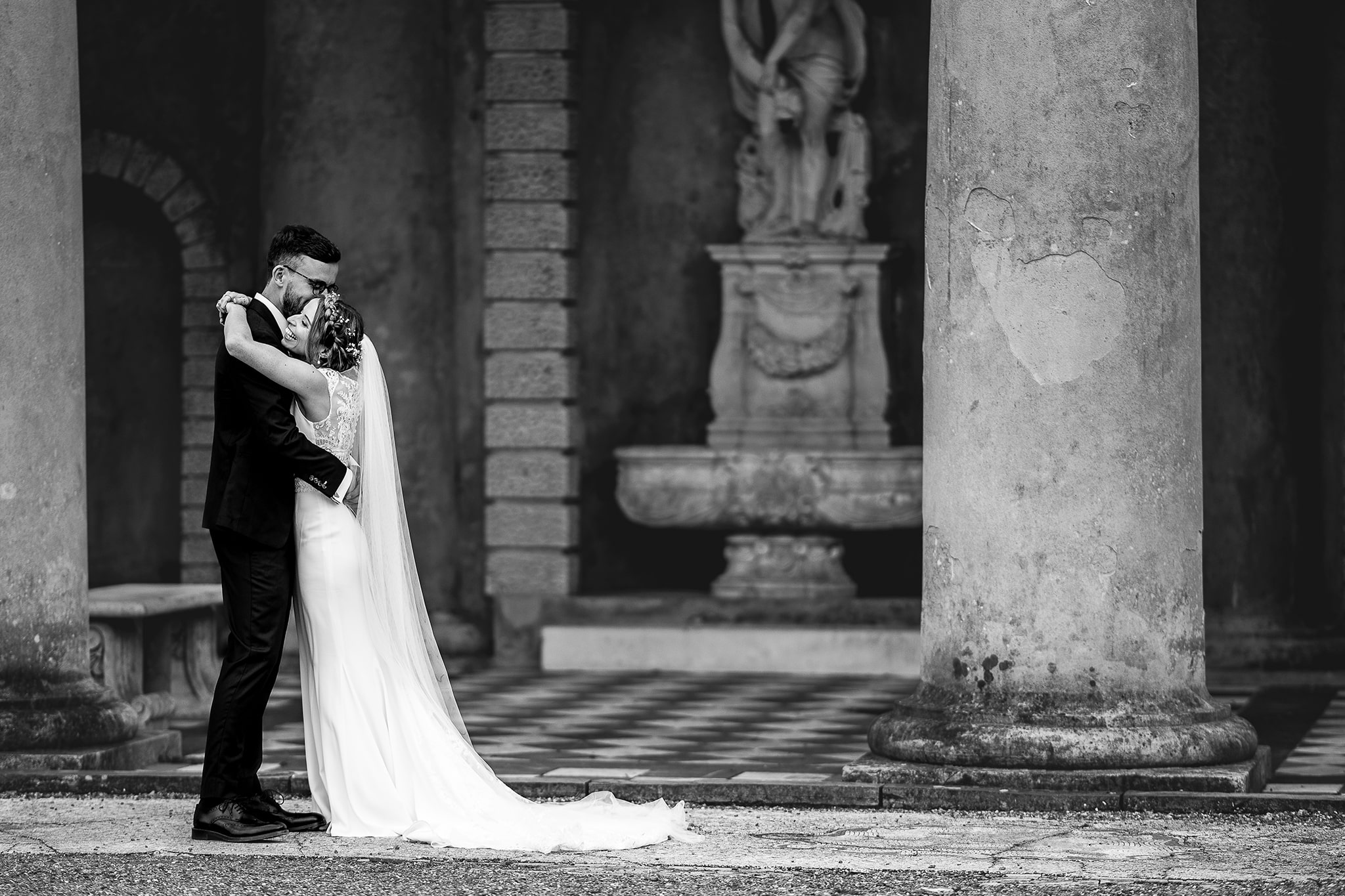Black and white photo of Bride and Groom embracing at WOTTON HOUSE garden pavilian